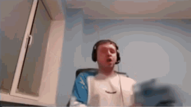 a man wearing headphones and a microphone is sitting in a chair .