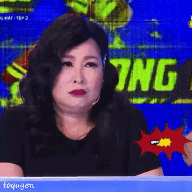 a woman is sitting in front of a screen that says gian luôn