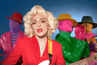 a woman in a marilyn monroe costume is standing in front of a group of colorful people