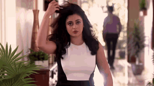 a woman in a black and white dress is standing in a hallway holding her hair .