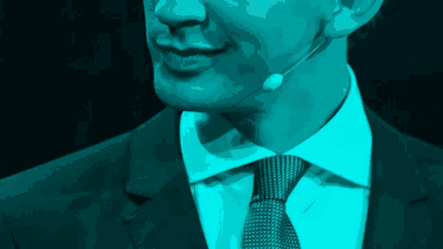 a man in a suit and tie has a microphone on his ear