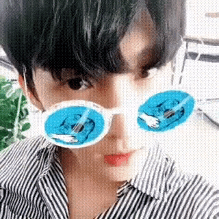 a young man wearing a striped shirt and sunglasses with a picture of a cat on them .