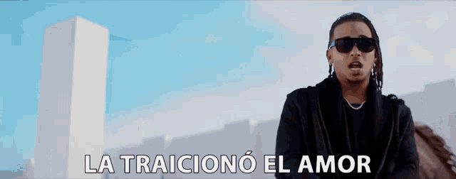 a man wearing sunglasses stands in front of a building with the words la traiciono el amor below him