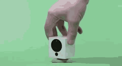a person is holding a white object with their finger .