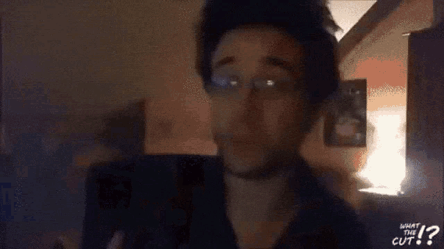 a man wearing glasses and a choker says what the cut on the bottom