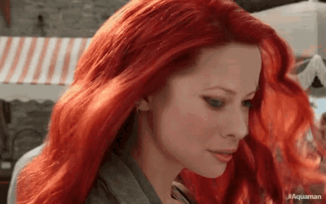 a close up of a woman with red hair looking down .