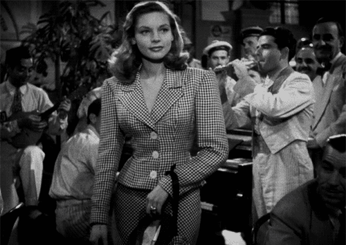 a woman in a plaid suit is standing in front of a crowd of people in a black and white photo .