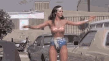 a woman in a wonder woman costume is standing next to a car .