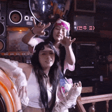two women are posing in front of a jukebox and a sign that says ' korean ' on it
