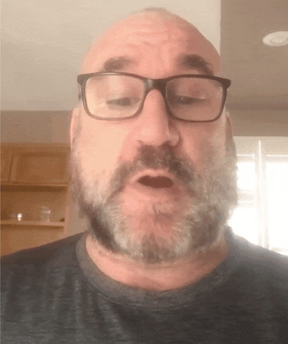 a man with glasses and a beard is making a face