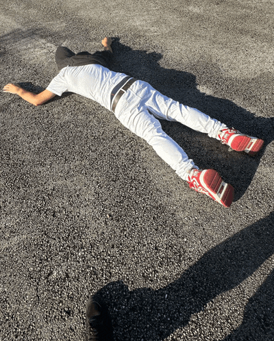 a man laying on the ground wearing a white shirt and white pants with red shoes