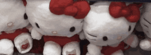 a bunch of hello kitty stuffed animals are sitting on top of each other .