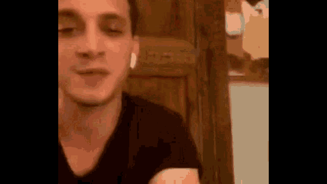 a man wearing ear buds is sitting in front of a wooden door with his eyes closed .