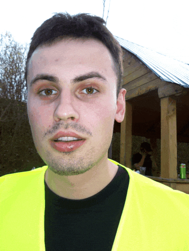 a man wearing a yellow vest and a black shirt