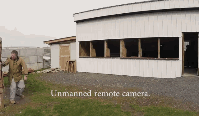 a man standing in front of a white building with the words unmanned remote camera