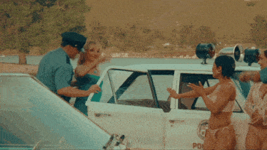 a woman in a bikini talks to a police officer in a police car