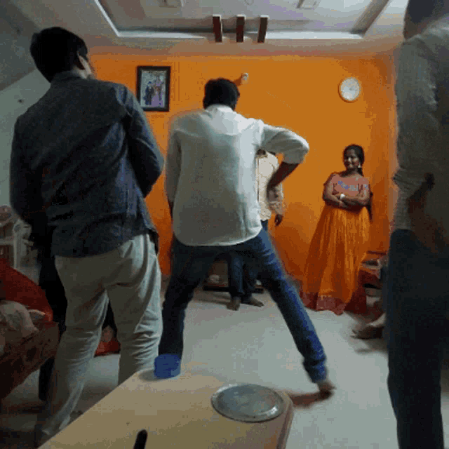 a group of people are dancing in a living room with a clock on the wall