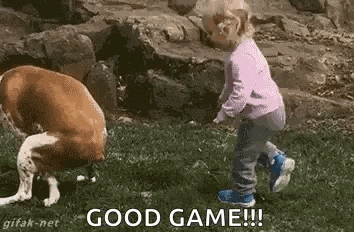 a little girl is playing with a dog in the grass and the dog is looking at the little girl .