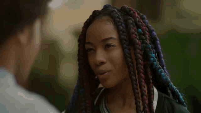 a woman with braids looks at a man with a serious look on her face
