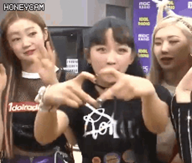 a group of girls are making a heart shape with their hands while standing next to each other .