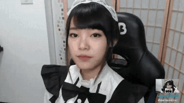 a girl in a maid costume is sitting in a black chair with the letter b on it
