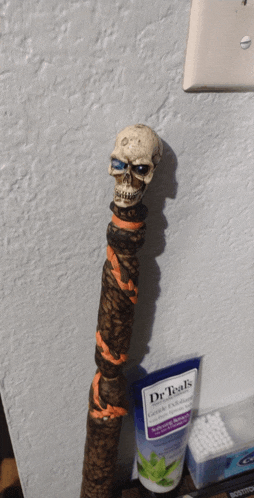 a cane with a skull on top of it next to a tube of dr teal 's gentle exfoliating cream
