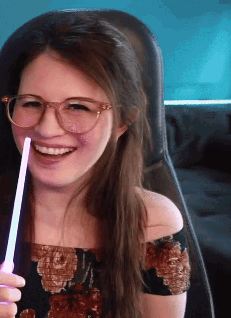 a woman wearing glasses is holding a glow stick in her hand