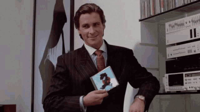 a man in a suit and tie is holding a cd with a dragon on it