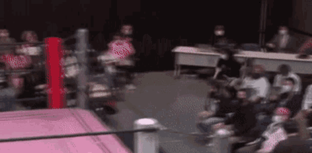 a blurry picture of a wrestling ring with people sitting in the stands .