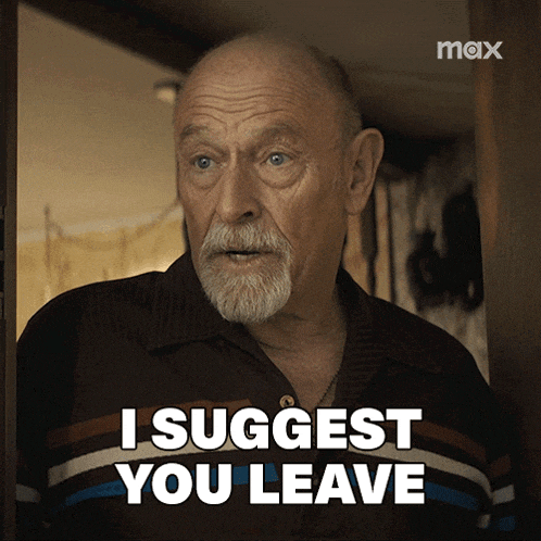 a man with a beard is standing in a doorway and says " i suggest you leave "