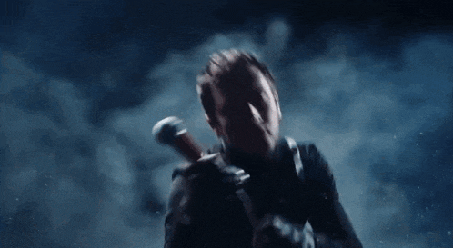 a man is holding a sword in his hand in a dark room with smoke coming out of it .