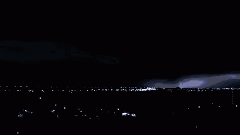 lightning strikes in the night sky over a dark city