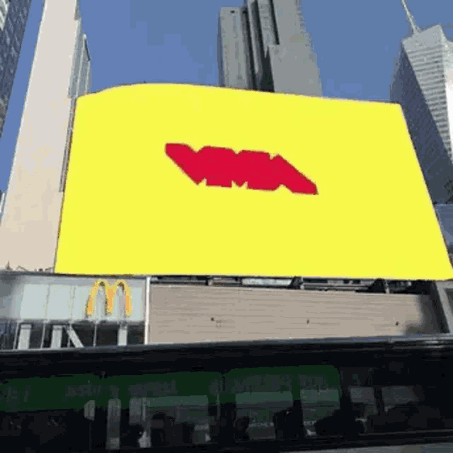 a large yellow sign with a red arrow on it is on the side of a building in a city .