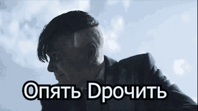 a man in a suit with a shaved head and the words " опять дрочить " in white letters