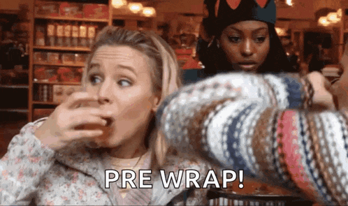 a woman is covering her mouth while another woman holds a sweater and says pre wrap !