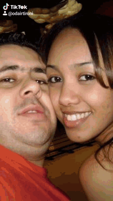a man and a woman are posing for a picture and the woman is smiling .