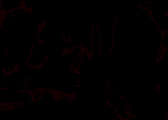 a woman with red hair is sitting in front of a fire in a dark room