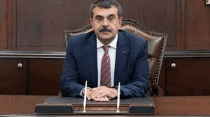 a man in a suit and tie is sitting at a desk in a room .