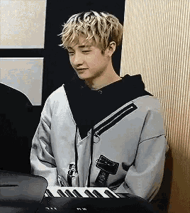 a young man is sitting at a table with a keyboard and a microphone .