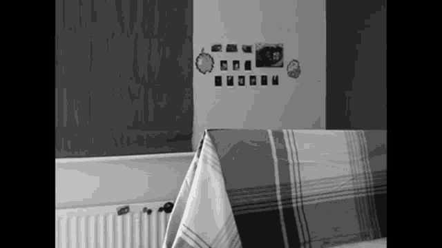a black and white photo of a table with a plaid tablecloth and pictures on the wall behind it