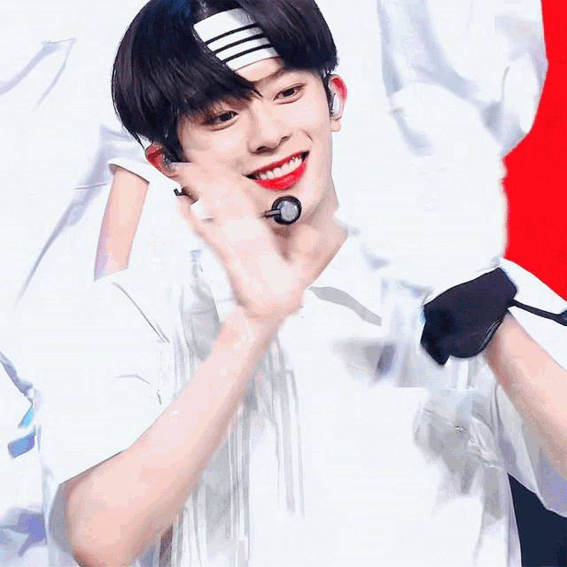a young man wearing a headband and a microphone smiles for the camera