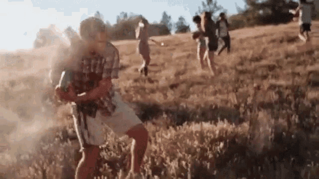 a group of people are standing in a field playing with water .