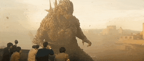 a group of people are standing in front of a statue of a monster .