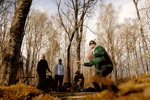 a man in a green jacket is throwing a frisbee