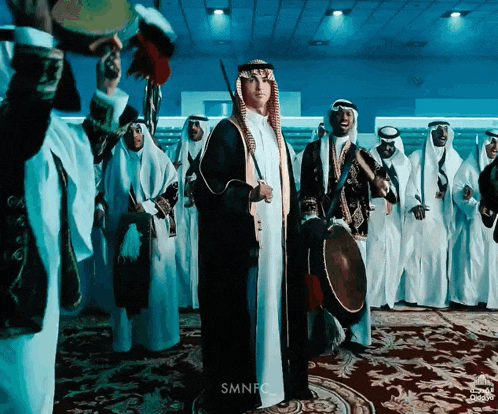 a group of men are standing in a room with smnfc at the bottom