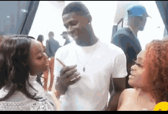 a man and a woman are standing next to each other at a party and the woman is kissing the man on the cheek .