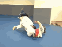 two people are wrestling on a blue mat in a gym .