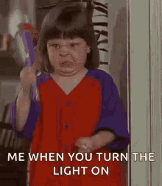 a little girl is holding a toothbrush in her hand and making a face .