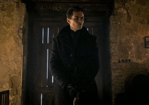 a man in a black coat stands in front of a brick wall with a picture on it that says 1906
