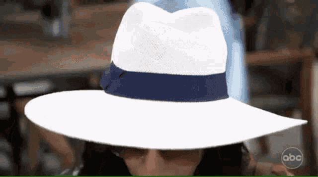 a woman wearing a white hat with a blue ribbon and a abc logo